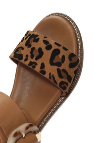 Sandalia deslizable marrón con una correa de ante de estampado de leopardo. Plantilla texturizada, parte inferior de cuero y acento de hardware en tono dorado en la correa.