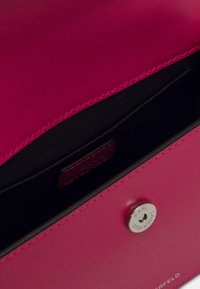 Różowa skórzana torebka od wnętrza z czarną podszewką, wyposażona w srebrny zatrzask i wytłoczoną metkę marki. Gładka tekstura i minimalistyczny design.