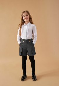 Fehér, hosszú ujjú ing, gombos elülső résszel, magas derekú, szürke sorttal, arany gombokkal, és fekete harisnyával, cipővel.