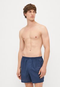 Ναυτικές μαγιό βερμούδες με ελαστική μέση, ελαφρύ ύφασμα και άνετη εφαρμογή. Διαθέτουν μικρές τετράγωνες φιγούρες σε πλέγμα.