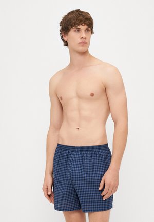 Mornarice kratke kupaće hlače s elastičnim pojasom, lagani materijal i opušteni kroj. Sadrži male kvadrate u uzorku mreže.