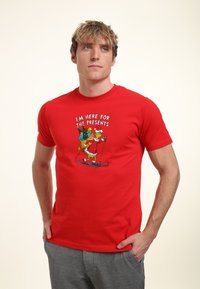 Rode katoenen t-shirt met een grafische print van skithema-personages en de tekst "IK BEN HIER VOOR DE CADEAUS" in het wit.