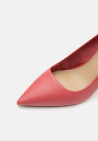 Chaussure plate rouge à bout pointu avec dessus en cuir lisse et doublure intérieure beige vue de dessus sur fond blanc.