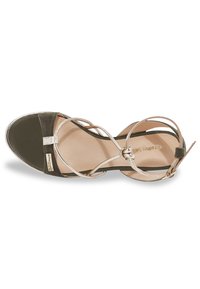 Sandal in suede verde con accenti argento. Presenta cinturini incrociati e punta arrotondata. Cinturino alla caviglia per una vestibilità sicura. Fodera interna liscia.