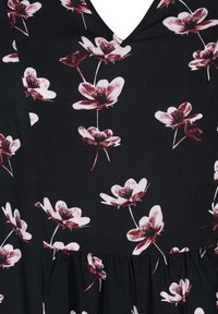 Svart tyg med en rynkad söm och ett rosa och vitt blommönster som har detaljerade blommande blommor.