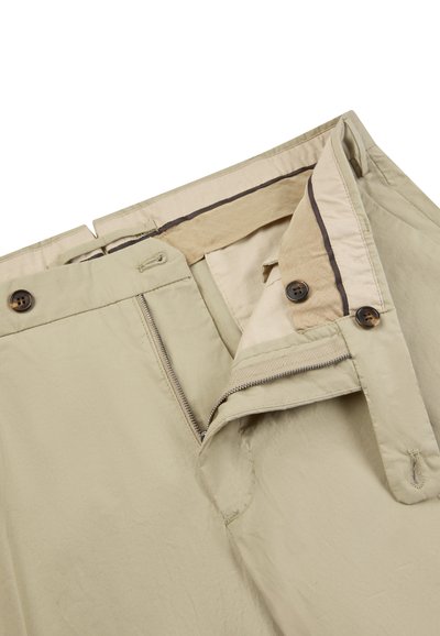 Pantalon beige avec braguette zippée, deux boutons à la taille et doublure intérieure beige visible avec bordure sombre.