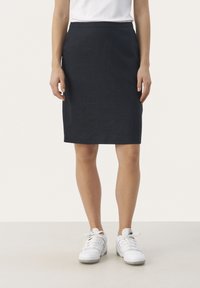 Navy blaue Bleistiftrock aus strukturiertem Stoff. Hat eine figurbetonte Silhouette, knielangen Schnitt und einen glatten Bund. Getragen mit weißen Turnschuhen.