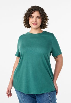 Morska bawełniana koszulka z krótkim rękawem, lekko luźnym krojem, okrągłym dekoltem i subtelną teksturą. Nosi się ją z dżinsami z wysokim stanem.