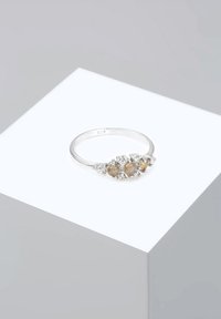 Anello in argento sterling con cinque pietre sintetiche disposte a grappolo, con dettagli trasparenti attorno alle pietre centrali. Contrassegnato 925.