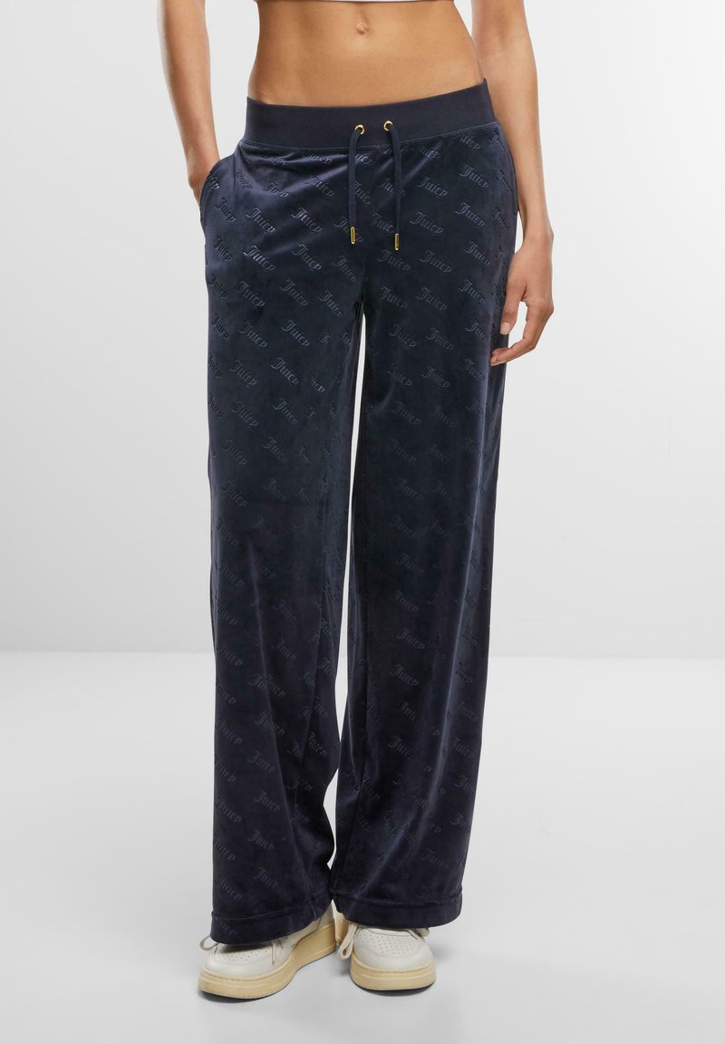 Navy velour sweatpants with a relaxed fit, featuring an elastic waistband, drawstring, and repeating logo pattern on the fabric.