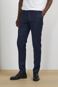 Pantalones de vestir azul marino, hechos de una tela suave, con un corte ajustado, frente liso y bolsillos laterales. Llevados con zapatos de vestir negros.