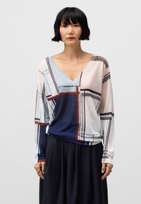 Lekki, wzorzysty sweter z dekoltem w serek, z niebieskimi, białymi, czerwonymi i czarnymi geometrycznymi wzorami. Długie rękawy, miękka tekstura.