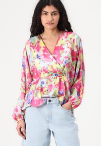 Blusa avvolgente floreale caratterizzata da colori vivaci di rosa, verde e blu, con un tessuto testurizzato, maniche lunghe e un dettaglio di vita cintata.