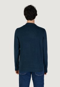 Maglione lavorato a maglia blu navy con maniche lunghe e scollatura rotonda, caratterizzato da una trama morbida e una vestibilità comoda, abbinato a jeans blu.