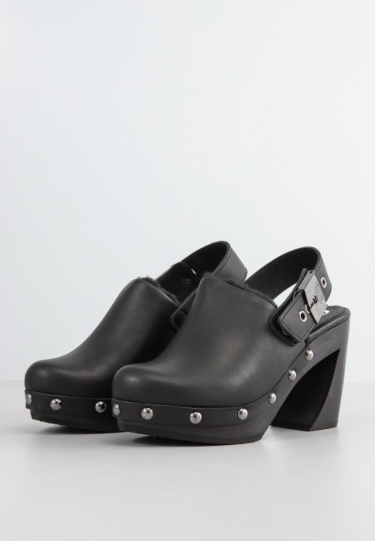 Schwarze Lederclogs mit hohen Absätzen, abgerundeter Zehenpartie, einem Slingback-Riemen und silbernen Nietenakzenten entlang der Sohle.