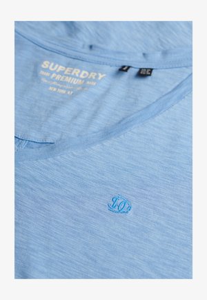 Lichtblauw katoenen T-shirt met een V-hals. Heeft een subtiel, geborduurd "10"-logo rechtsonder. Zachte textuur met een gemêleerd patroon.