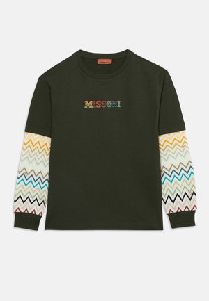 Chemise vert foncé à manches longues avec des manches à motif zigzag multicolore et un texte zigzag multicolore assorti sur la poitrine.