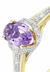 Prsteň s ametystom s veľkým fialovým drahokamom, zasadený do bieleho zlata, s diamantovými akcentmi pozdĺž obrúčky a zlatými pazúrikmi.