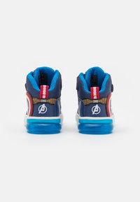 Sneakers com tema dos Vingadores, apresentando um cabedal azul-marinho, colarinho acolchoado, detalhes em vermelho e uma sola azul translúcida. Detalhes de logotipo notáveis nas laterais.