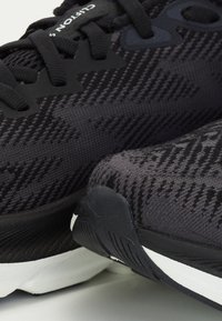Scarpe sportive nere con tomaia in maglia testurizzata, motivo geometrico, lacci neri e suola bianca con dettagli in gomma.