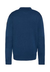 Niebieski sweter o dzianinowym wzorze z fakturowaną częścią na ramionach i ściągaczami. Posiada klasyczny kołnierzyk oraz małą naszywkę z logo na górnej części ramienia.