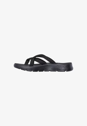 Sandalo nero slip-on con cinturini incrociati in tessuto e suola imbottita texturizzata, visto di profilo su sfondo bianco.