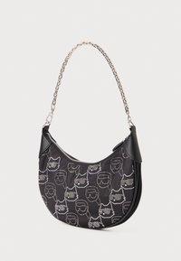Sac à main en nylon noir avec une bandoulière en chaîne, arbore un motif répété de visages en contour en strass argentés. Fermeture éclair en haut et design élégant.