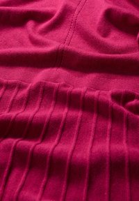 Tessuto a maglia fucsia caratterizzato da sezioni lisce intervallate da pieghe verticali, con dettagli di cucitura fine. Texture morbida.