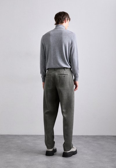 Maglione grigio a maniche lunghe con colletto alto abbinato a pantaloni in velluto a coste di colore verde scuro. I pantaloni presentano due tasche posteriori con chiusura a bottone.