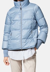 Light blue puffer jacket with a high collar, zip front, and ribbed cuffs. Features a quilted design and two side pockets.
