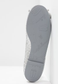 Sole di ballerina in glitter argento con logo impressionato e design di scarpette da ballerina. Tessuto morbido, forma arrotondata e costruzione flessibile.