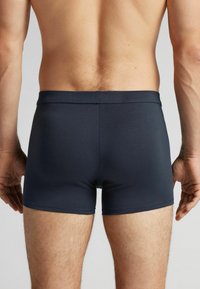 Mörkblå boxershorts med en åtsittande design, tillverkade av mjukt, elastiskt tyg. Har en sömlös midja och minimalistisk konstruktion.