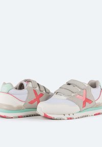Zapatillas ligeras con parte superior de malla en gris y blanco, acentos en rosa y correas de velcro. Suela de goma con detalles en verde menta y acabado texturizado.