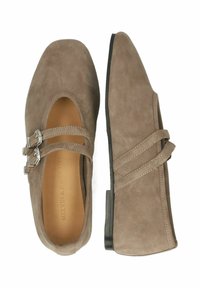 Beige színű velúr lapos cipők négyzetes orral. Két pántos részlete van fém csattal, valamint egy alacsony, hegyes sarokkal. Texturált felület.