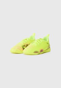 Scarpe da ginnastica neon gialle con tomaia texturizzata. Presentano motivi a onda colorati e un design a taglio basso. Include lacci e un pull tab sul tallone.