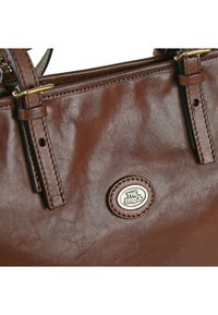 Borsa a spalla in pelle marrone con tracolle regolabili e una piccola piastra metallica ovale con il logo in rilievo "THE BRIDGE".