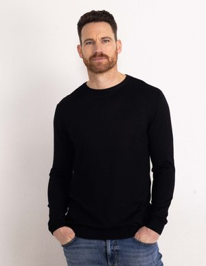 Black long-sleeve sweater with a crew neckline, ribbed cuffs, and hem. Worn over blue denim jeans, featuring a solid color with smooth texture.