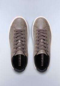 Un paio di sneaker in pelle taupe con lacci grigi spessi e suole bianche, viste dall'alto su uno sfondo grigio chiaro.
