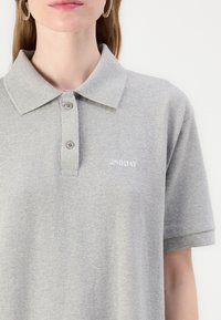 Grå polo skjorte laget av myk stoff, med krage, tre-knappslukking, og brodert "2ND DAY"-tekst på brystet.