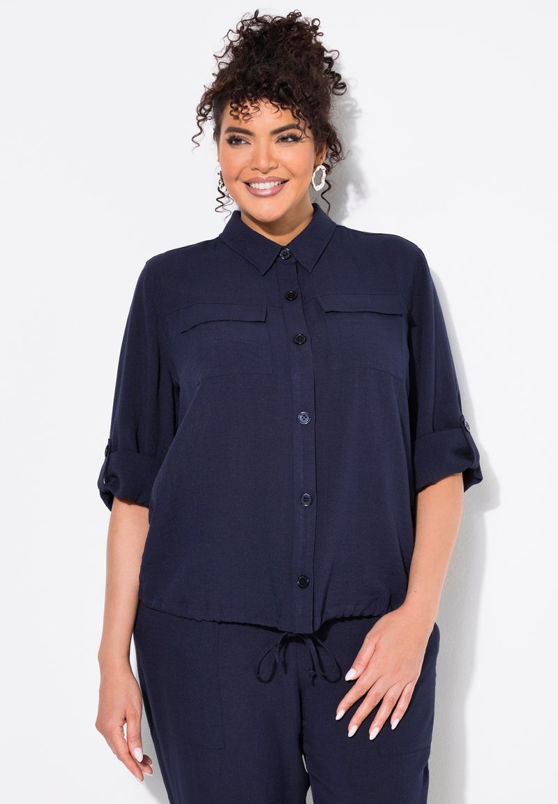 Camisa marinera de botones, con dos bolsillos en el pecho, mangas enrolladas y un dobladillo con cordón. Fabricada con un tejido ligero y de textura suave.