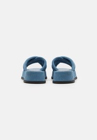 Sandali in tessuto blu con cinturini larghi. Suola piatta in gomma nera, design minimale e tessuto testurizzato visibile sui cinturini e sulla parte superiore.