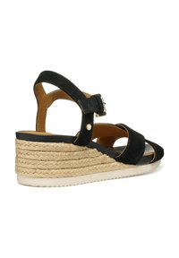 Sandalo con zeppa in suede nero e suola in juta intrecciata, dotato di cinturino alla caviglia regolabile e design aperto sulla punta. Fodera interna liscia e suola in gomma.