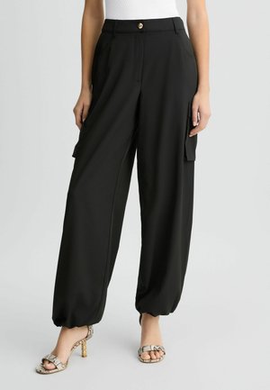 Pantalons cargo noirs avec taille haute, devant plissé, deux poches latérales et bas fuselés. Fabriqués à partir d'un tissu lisse et léger.