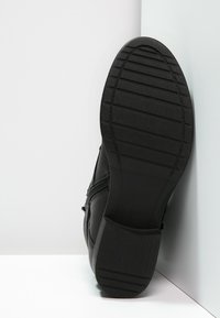 Stivale in pelle nera con suola in gomma, dotato di zip laterale, finitura testurizzata e tacco a blocco. Motivo di battistrada dettagliato sulla suola.