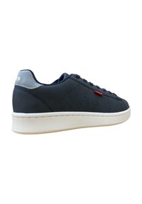 Zapatillas de color navy con una textura suave, suela blanca y acento en el talón gris contrastante. Presentan un diseño perforado y un detalle en rojo con el logo.