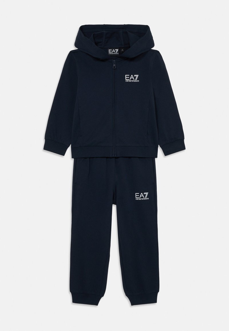 Conjunto de fato de treino azul marinho, composto por uma jaqueta com capuz e fecho e calças com punhos elásticos. Ambas as peças apresentam um logótipo branco da EA7 no peito e na coxa.