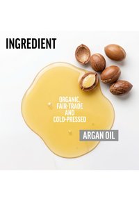 Huile d'argan dorée claire renversée près des noix et coques d'argan sur une surface blanche avec un texte la décrivant comme biologique, équitable et pressée à froid.