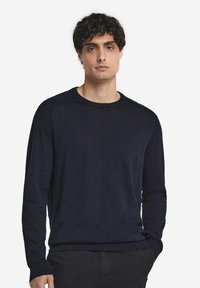 Marininblå långärmad tröja med rund hals, tillverkad av mjukt material, med ribbad mudd och nederkant, med en avslappnad passform och subtil textur.