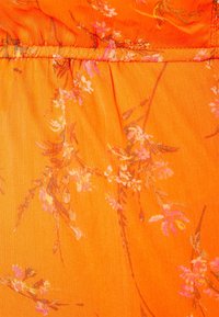 Tela con patrón floral en un vibrante color naranja, con flores rosas y blancas. El material parece ligero y tiene una textura suave.