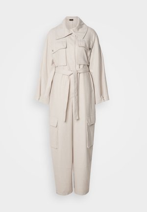 Beige jumpsuit lavet af tekstureret stof, med en stor krave, frontlommer, lange ærmer og en bælte i livet med en løs pasform.